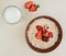 top view of bowl of oatmeal with cottage cheese chocolate and strawberries with glass of milk on white background