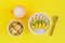 Top view on bowl of oatmeal decorated with banana, kiwi, mango, coconut chips and bowl of homemade cookies with cup of milk.