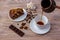 Top view of a bowl with sugar cubes, coffee beans, a piece of amazing cake on a saucer and a cup of coffee, anise and chocolate ba