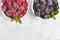 Top view of bowls with frozen blueberries and raspberry on a light concrete background. Place for text