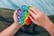 Top view on boy`s hands playing with rainbow pop it fidget toy. Push bubble fidget sensory toy - washable and reusable silicone