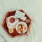 Top view Breakfast in bed with Have a nice day text on lighted box. Cup of coffee, juice, macaroons, flower on wooden tray. Good