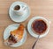 Top view of a breakfast with chocolate croissant, milk with cocoa powder and coffee