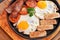 Top view, Breakfast consists of fried eggs, bacon, tomatoes and bread on wooden table.