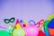 Top view bright party tools and decoration - baloons, funny carnival masks, festive tinsel on lilac background. Happy birthday gre