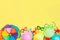 Top view bright party tools and decoration - baloons, funny carnival masks, festive tinsel on yellow background. Happy birthday gr