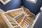 Top view of bright spiral staircase with polished wood parquet steps and matte white railings set against blue walls