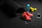 Top view of bright yellow dumbbells, a mat, bottle of water, sports shoes and phone on a black floor background.