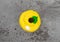 Top view of a brightly frosted yellow cupcake on a gray background
