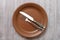 Top view of brown plate with flatware on gray