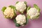 Top view of bunch of white and yellow cauliflower vegetables on pastel pink background