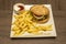 Top view of burger garnished with french fries, sauces, white onion