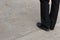 Top view of a business man& x27;s legs in black leather pants and shoes standing on the pavement