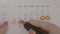 Top view of business woman hands signing vacation days on calendar with red pen -