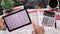 Top view of businessman`s hands working with tablet pc and financial reports. Modern black office desk with notebook, pencil and a