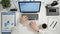 Top view businessman working on laptop with graphs and charts at office desk