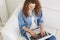 Top view of busy concentrated woman with curly hair, typing information, searching in net, looking attentively at laptop screen,