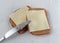 Top view of a butter knife atop two slices of wheat bread with margarine and cheese on paper towels