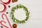 Top view of candy canes, two cups of cocoa and christmas pie with icing on white wooden table.