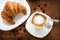 Top view of cappuccino coffee with croissant.