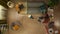 Top view capturing a young woman standing in the center of the furnitured room, vacuuming the floors.