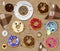 Top view of cartoon food with eyes, mouth and hands. A wooden table with doughnuts, cookies, coffee, drinks and other