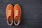 Top view of casual orange suede trainers on grey wooden planks