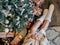 Top view of a caucasian girl wearing white fuzzy socks, sitting under the Christmas tree