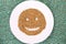 Top view of cereal in a white plate shaped like a smiley face, on a patterned surface