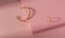 Top view of chain shape golden bracelet and ring on pink paper