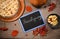 Top view chalkboard with Thanksgiving lettering next to dry autumn maple leaves homemade pumpkin pie with crispy crust