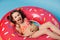 Top view charming little child girl with coconut drink, relaxing on floating donut swim ring, isolated blue background