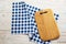 Top view of checkered napkin tablecloth on white wooden table. Empty cutting square board