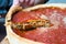 Top view of Chicago pizza. Woman hands cutting Chicago style deep dish italian cheese pizza with tomato sauce and beef meet inside