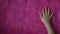 Top view of child hands touch and smooth out pink crumpled paper on table with copy space