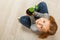 Top view of a child sitting on the floor and holding a young plant. The little girl is looking at the camera. The concept of