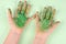 Top view children hands with paint over green background