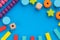 Top view on children`s educational games, frame from multicolored kids toys on blue paper background. Wooden bricks, cubes, stars