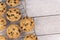 Top view of chocolate chip cookies on a cooling rack, white wooden plank in background.