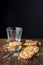 Top view of chocolate chip cookies, spoon and empty glass, with selective focus, on wooden table and black background