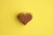 Top view of a chocolate heart-shaped bonbon isolated on a yellow background