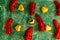 Top view of Christmas ornamental heart-shaped balls and peppers on green background