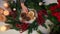 Top view Christmas wreath and burning candles on white table with female hand placing cup of cocoa to cookies in the