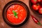Top view close-up of bowl of gazpacho soup and bowl of fresh tomatoes on brown background