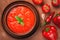 Top view close-up of bowl of gazpacho soup and fresh tomatoes with peppers on brown background