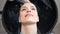 Top view close-up face of happy pleased woman during rinsing hair over sink at beauty salon