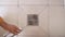 top view close-up of a man using silicone sealant treats the seams between the tiles in the bathroom.