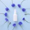 Top view and close-up of mockup of unbranded white plastic spray bottle and floral frame of blue lowers on a pastel blue