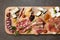 Top view closeup of an assortment of delicious cured meats and cheeses on a wooden board