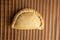 Top view closeup of a delicious empanada on a brown table